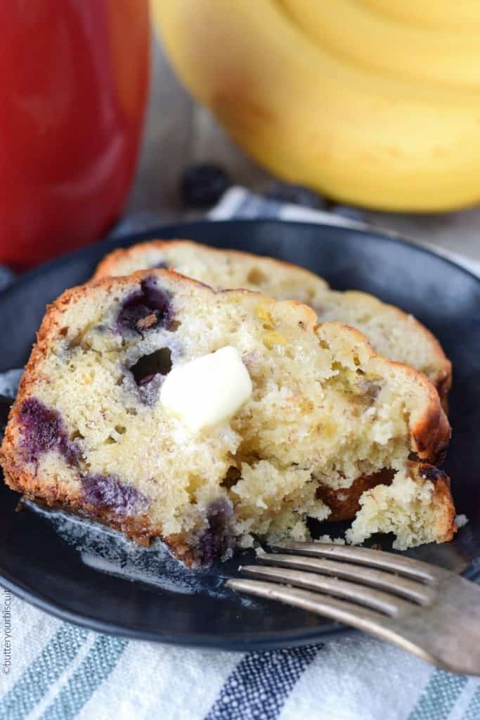 Banana Blueberry cream cheese bread on a black plate with a piec cut out