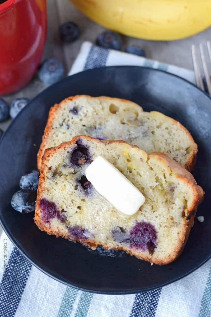 Banana Blueberry cream cheese bread on a black plate with a dab of melted butter