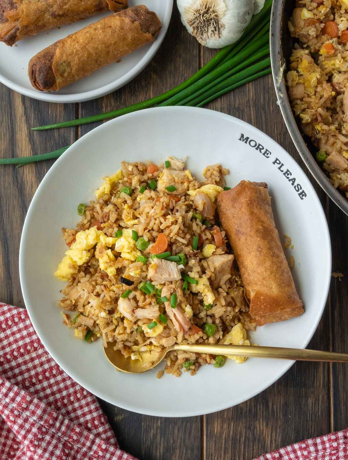 Chicken fried rice on a plate with an egg roll.