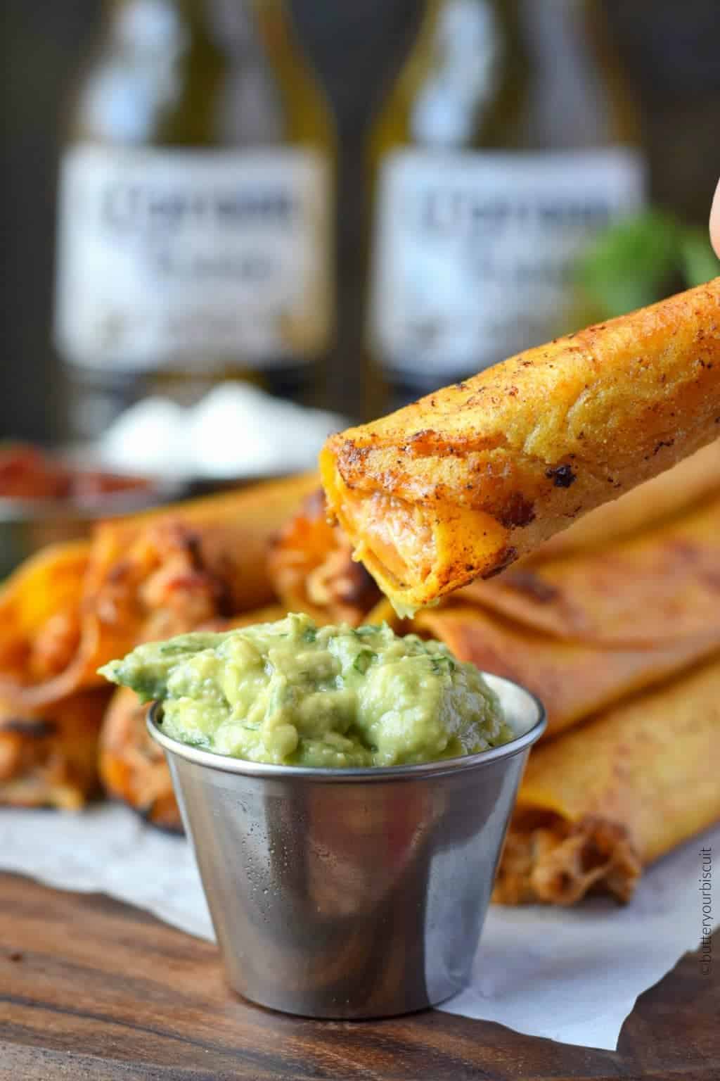 A taquito is dipped in guacamole.
