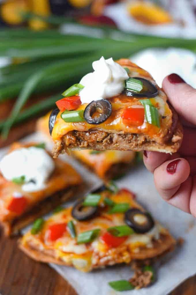 A slice of the Mexican pizze with a dollop of sour cream being picked up.