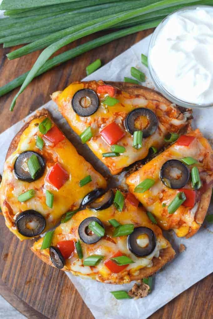 Mexican pizza cut into fours with a side of sour cream