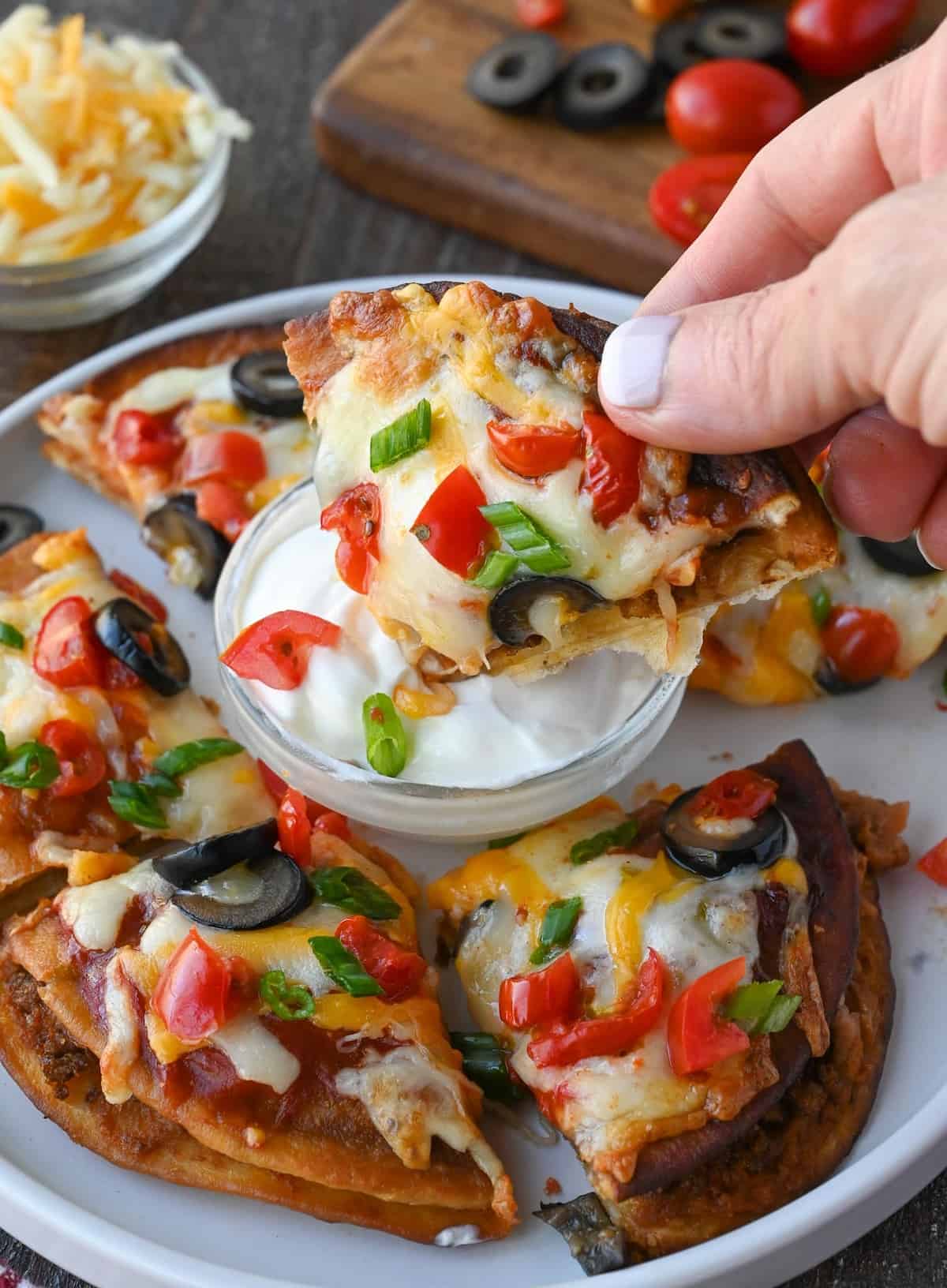 A slice of mexican pizza being dipped into sour cream.
