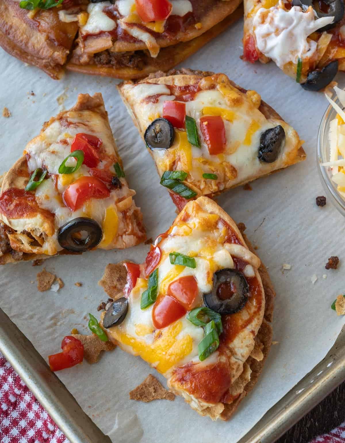 Mexican pizza cut into slices on a baking sheet.