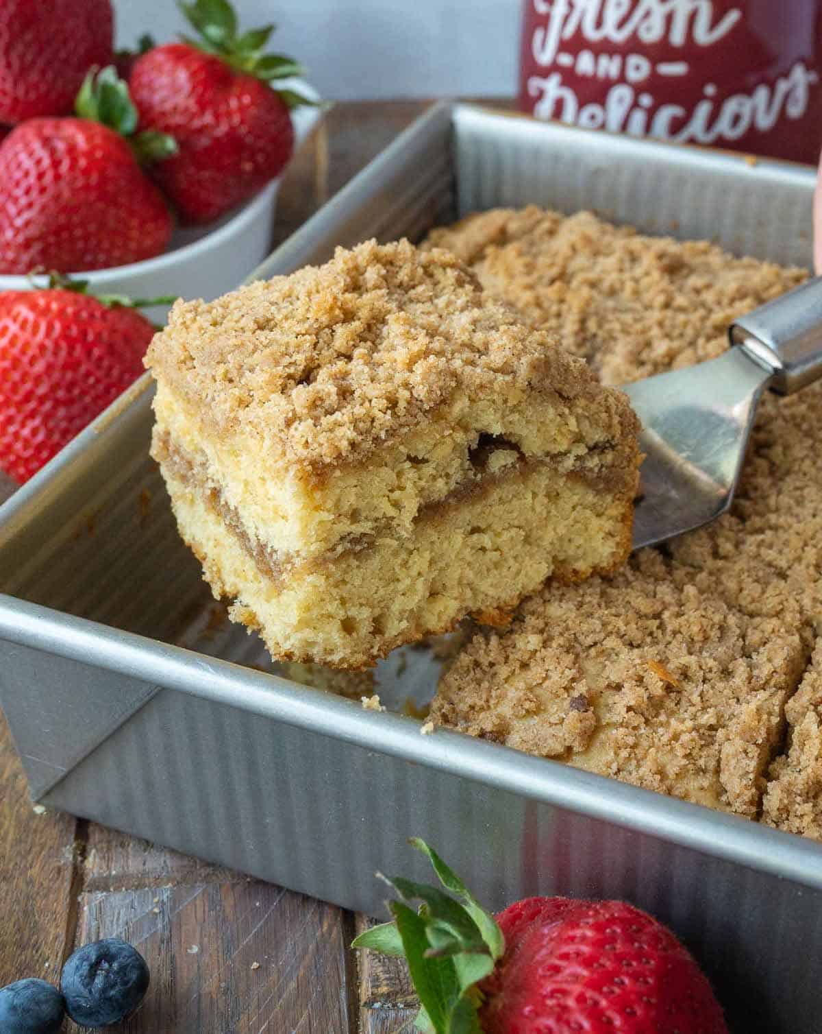 A spatula picking up a slice of sour cream crumb cake.