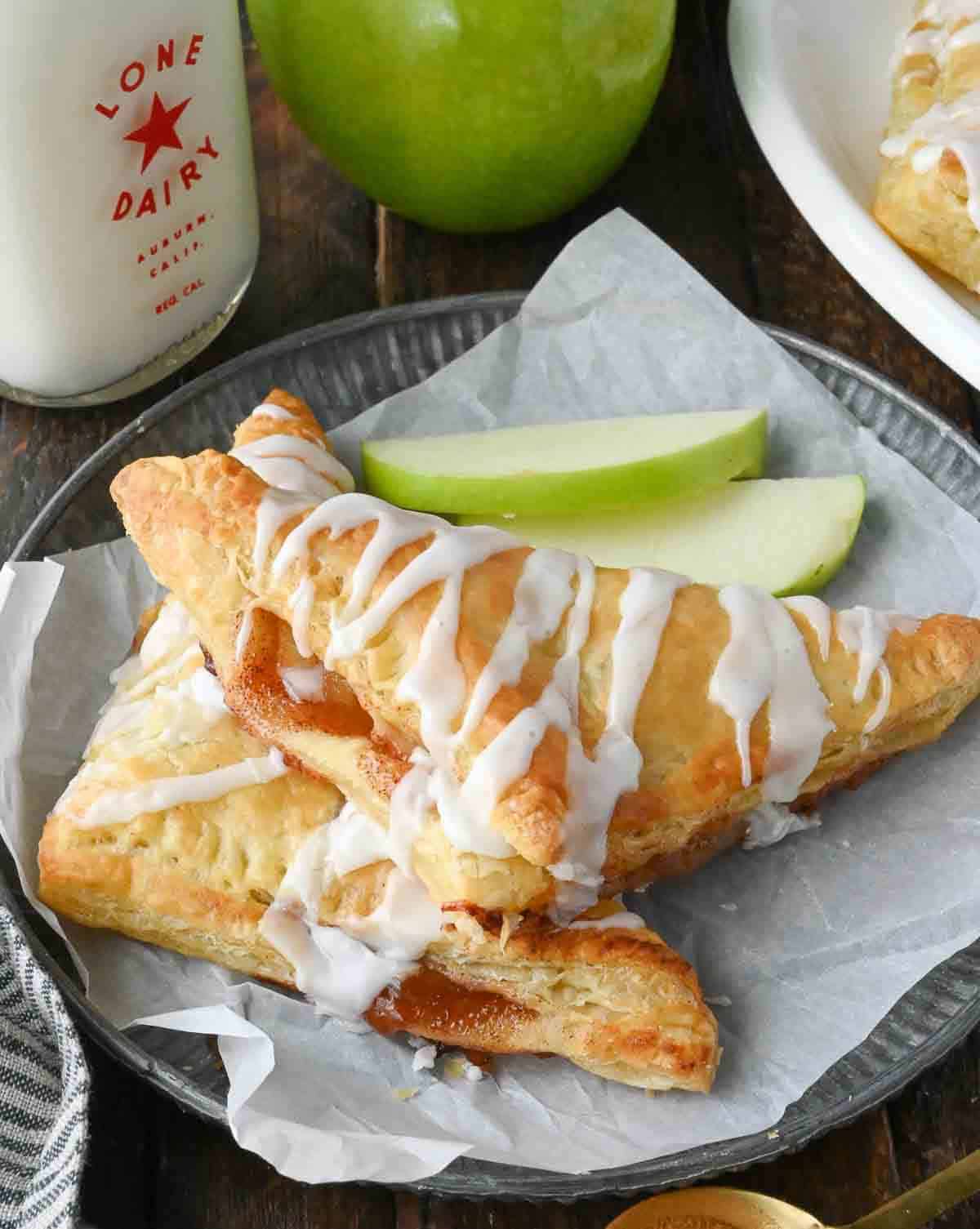 Apple pie turnovers on a plate with apple slices.