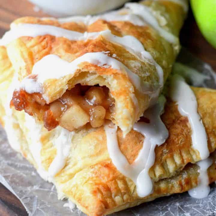 apple turnovers with glaze drizzle over top and a white coffee cup and green apple