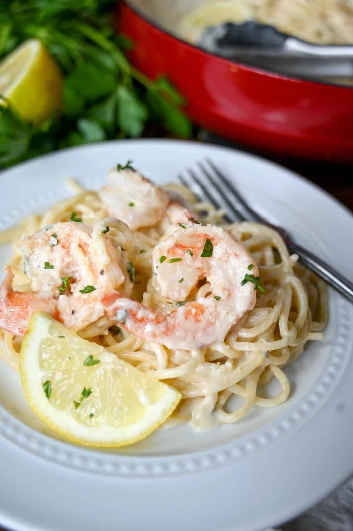 Close up shot of shrimp pasta. lemon slice and a fork.