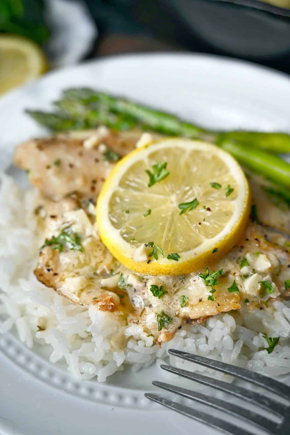 A plate of food with rice, tilapia and vegetables
