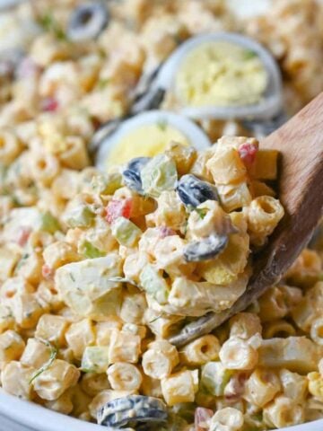 A wooden spoon scooping up some macaroni salad.