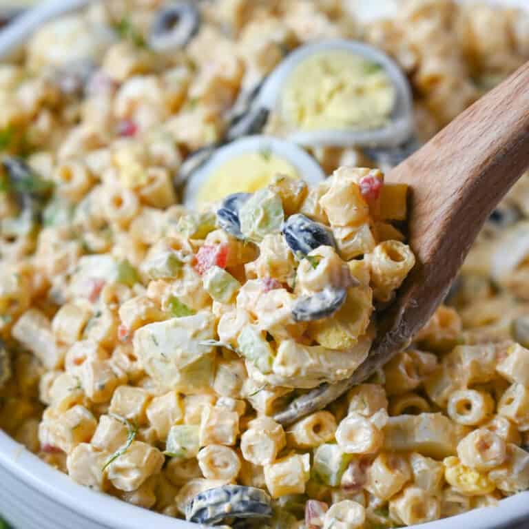 A wooden spoon scooping up some macaroni salad.