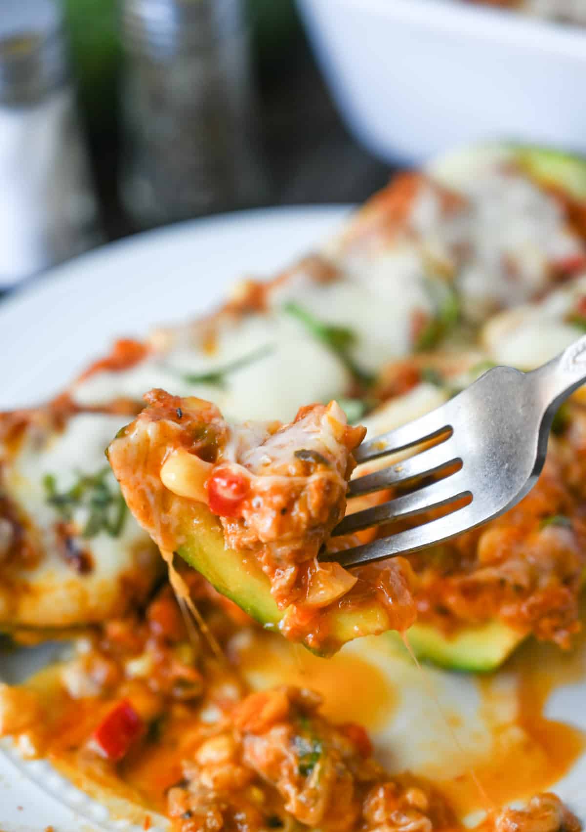 A bite of Italian sausage ztuffed zucchini on a fork.