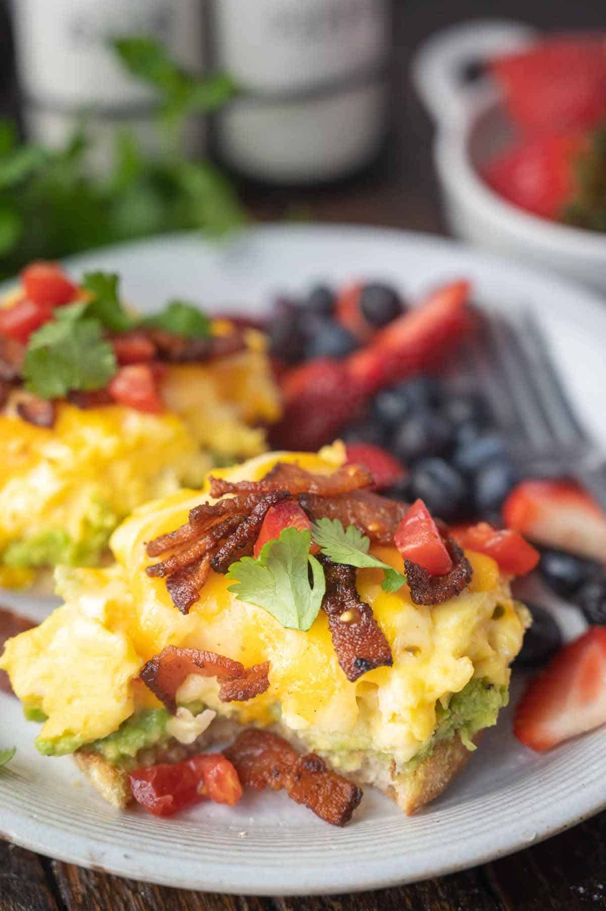 Open faced breakfast sandwich on a plate with a bite out of it.