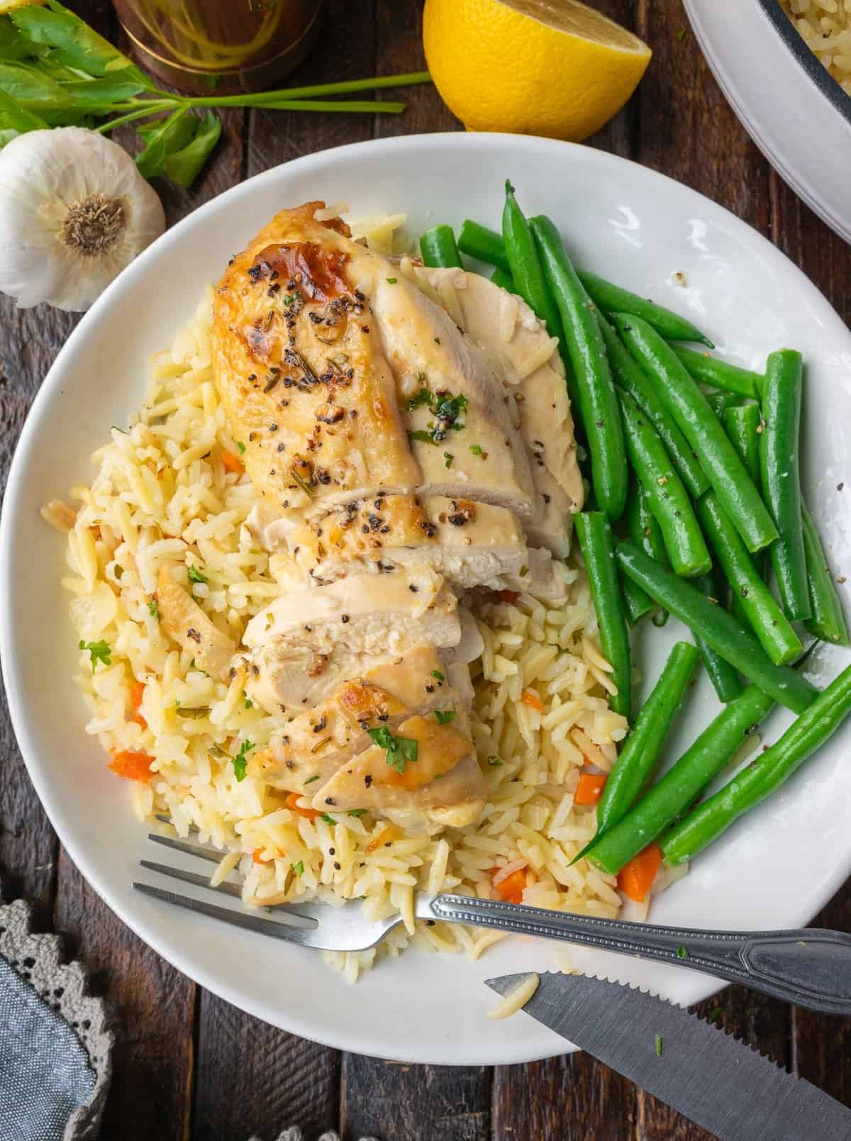 Lemon herb chicken with rice pilaf on a plate.
