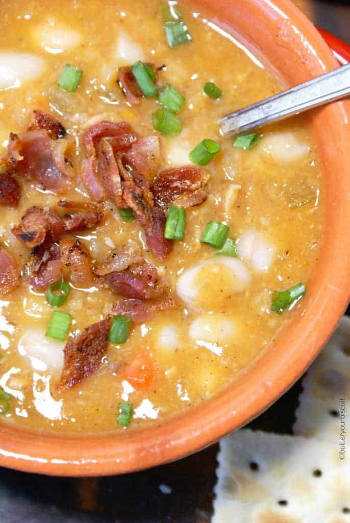 A close up photo of bean and bacon soup with a spoon.
