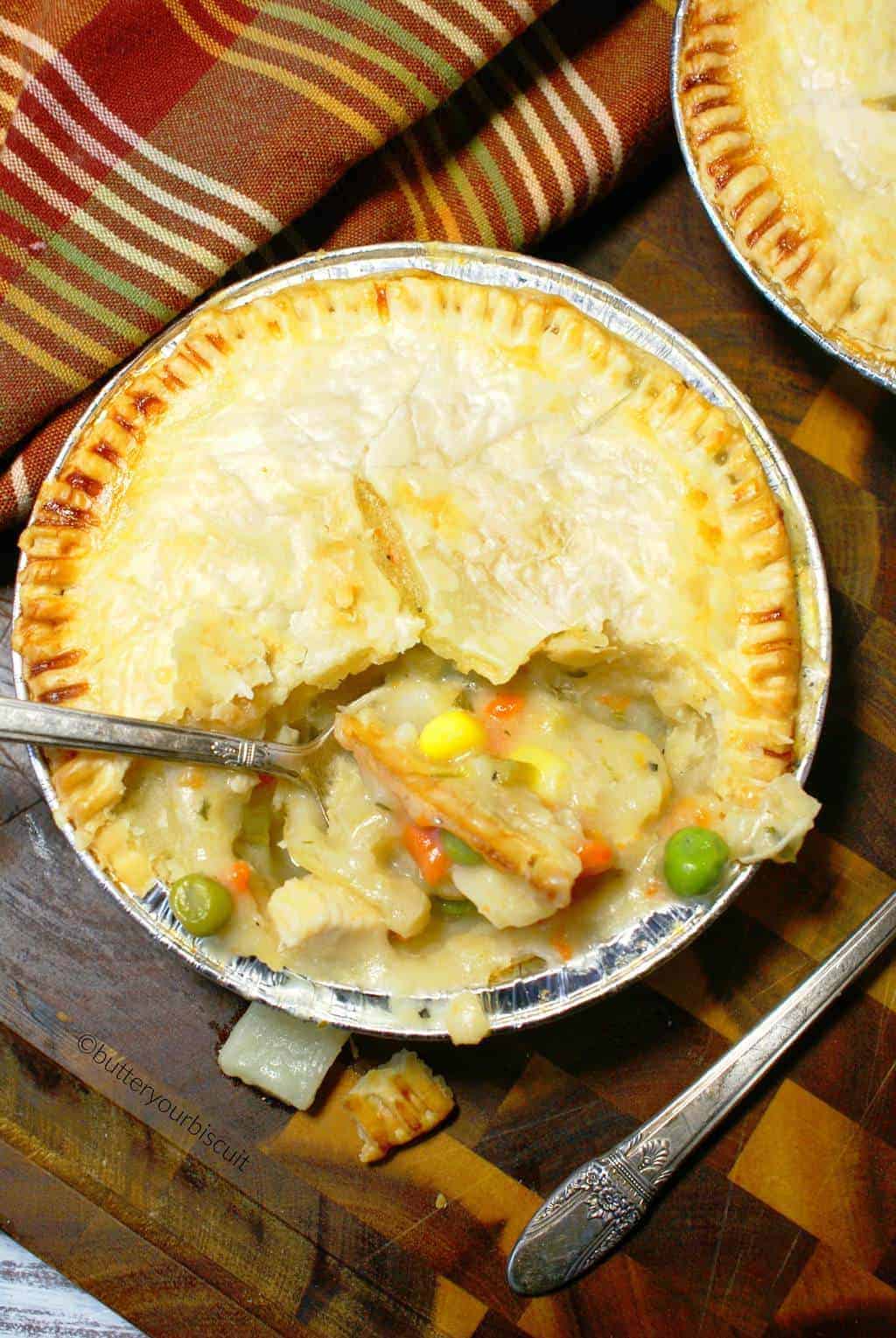 Two mini chicken pot pies on a cutting board with a bite out of one of them.