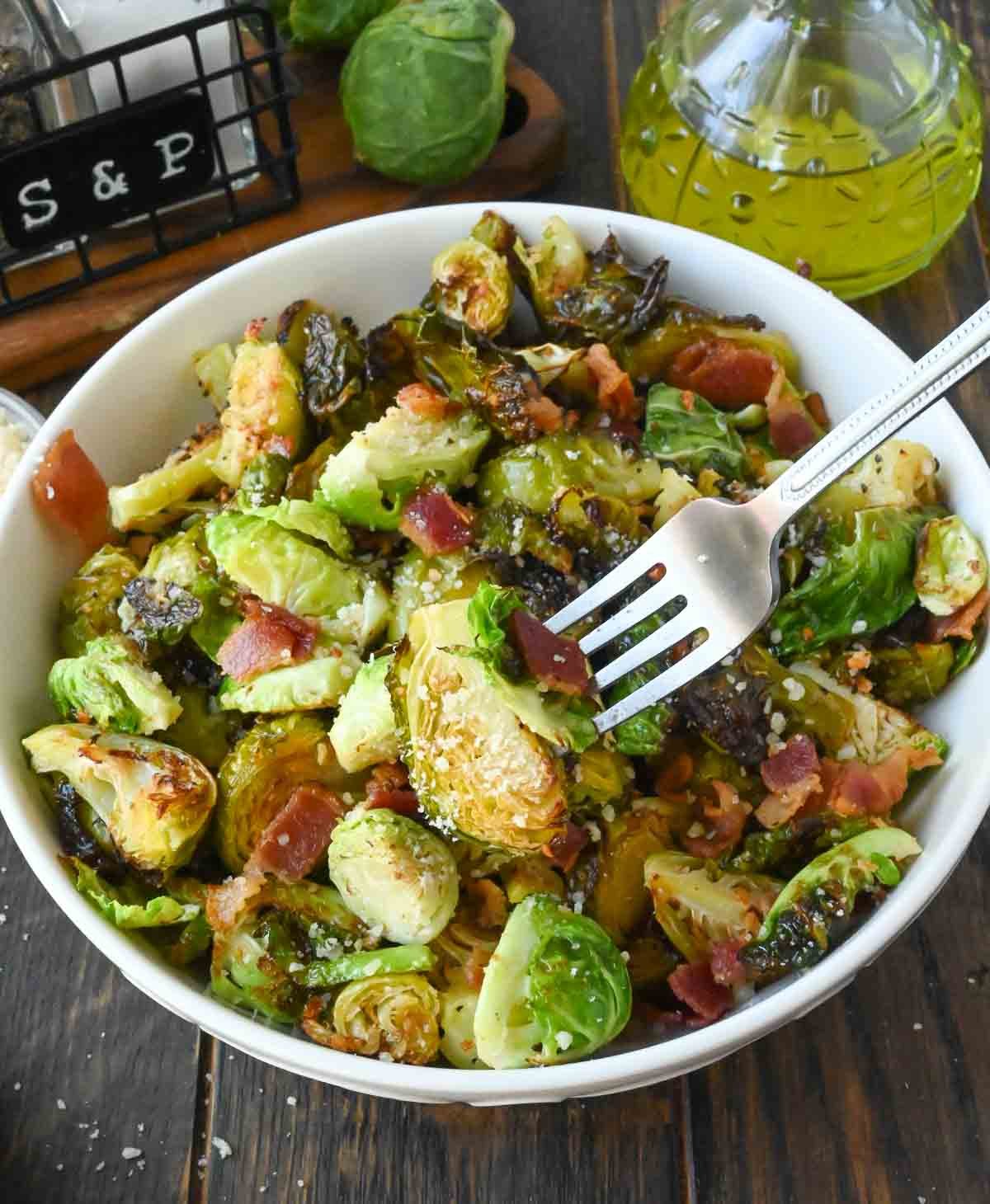 A bowl of parmesan roasted brussels sprouts with a fork.