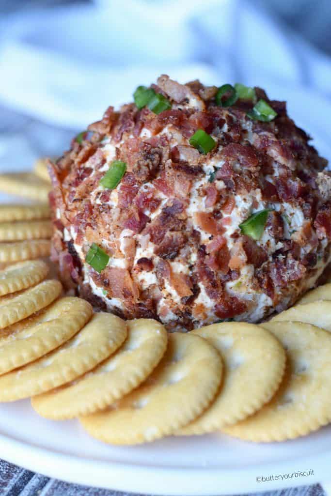 A large bacon jalapene cheese ball with ritz crackers placed all around it.