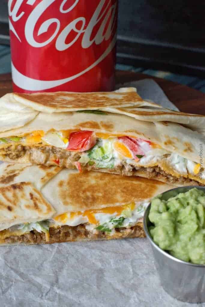 A crunch wrap cut in half with a side of guacamole