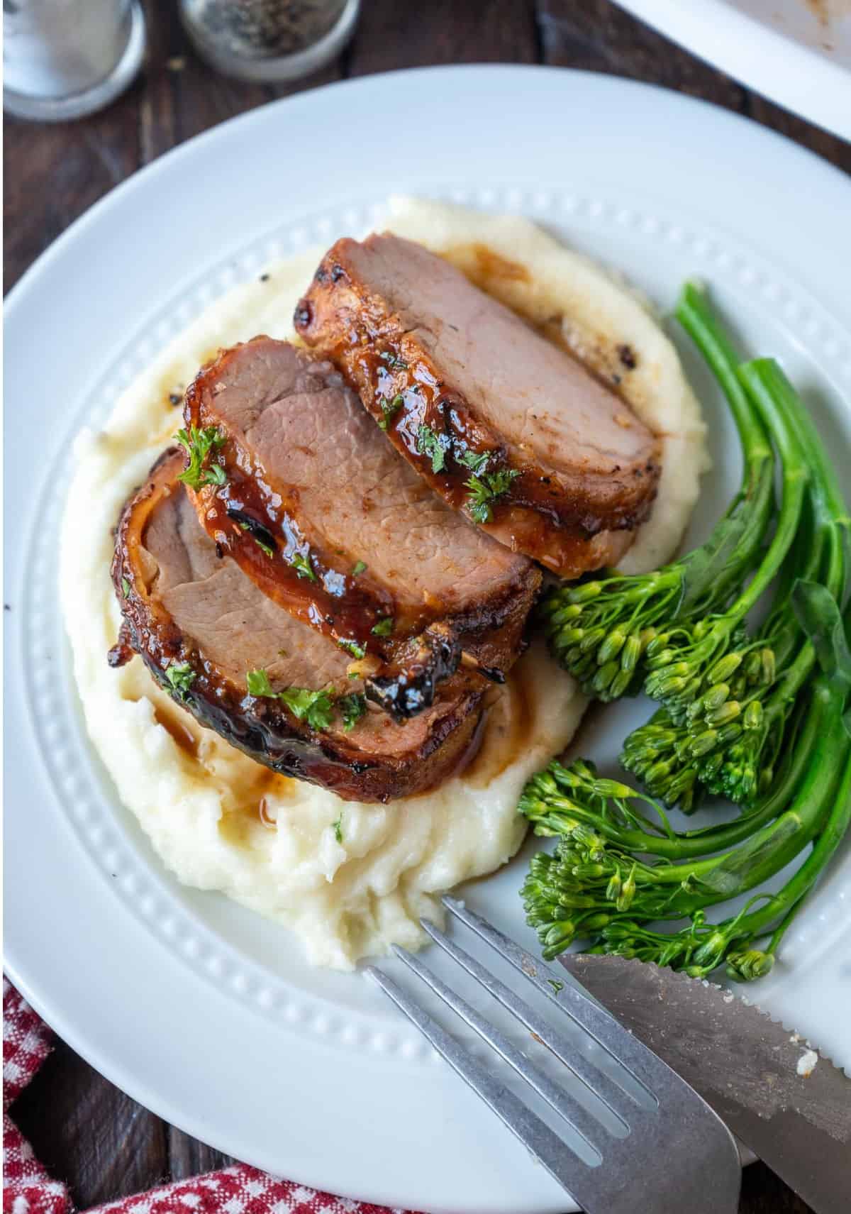 Three slices of pork placed on some mashed potatoes.
