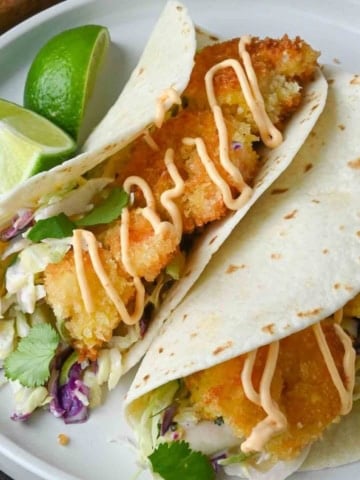 Crispy shrimp tacos on a white plate.