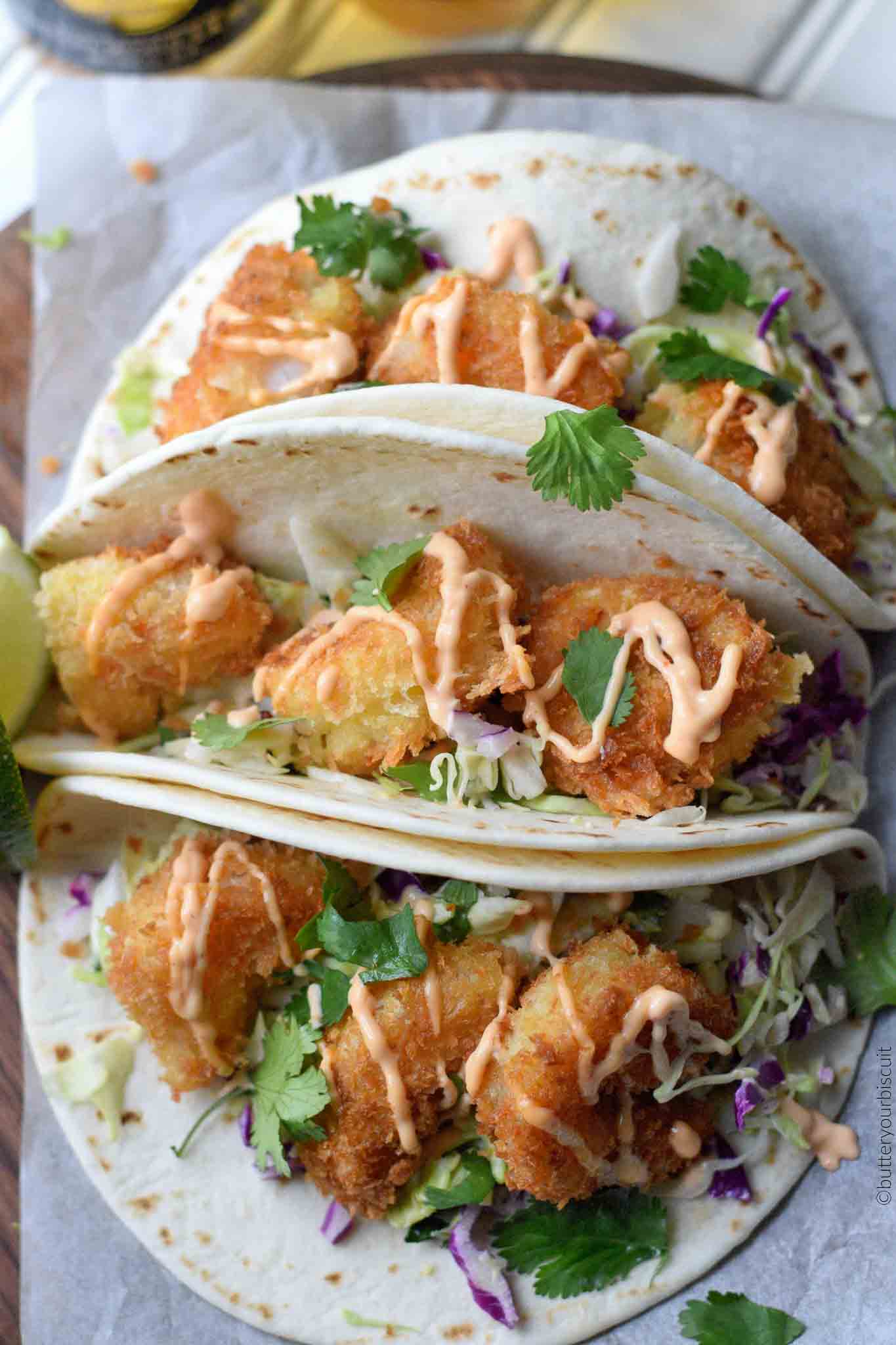 crispy shrimp tacos on a white plate.
