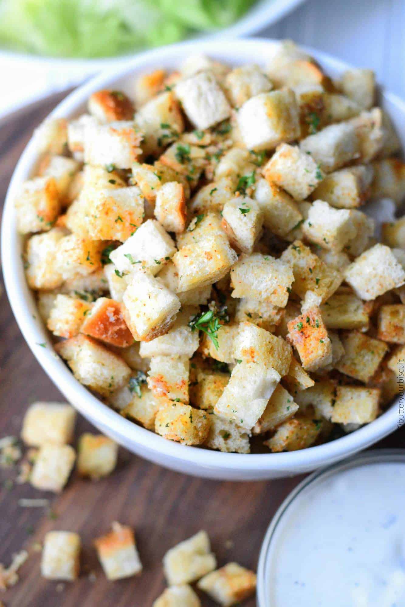 A bowl of croutons and a side of ranch dressing.