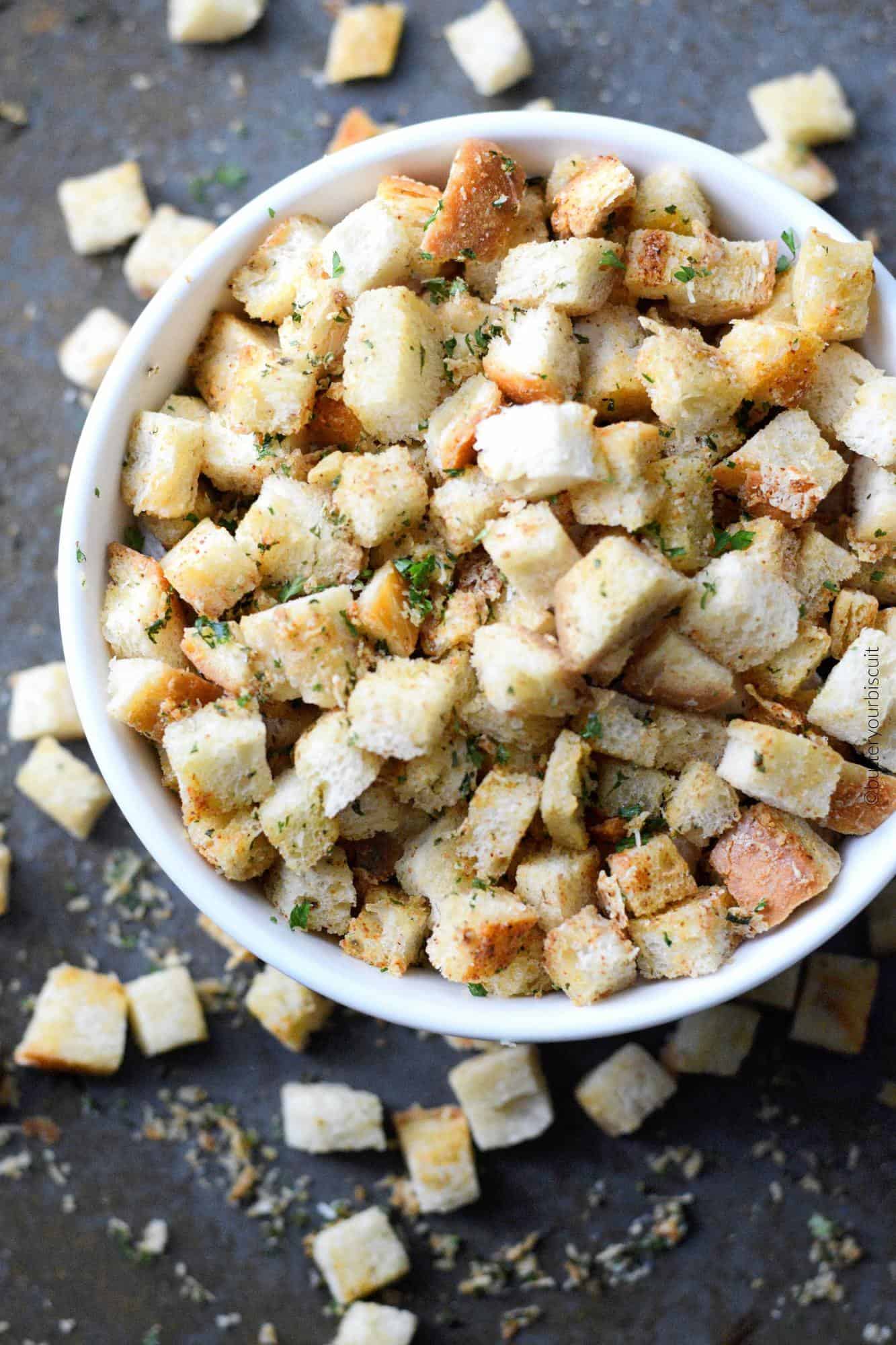 A white bowl full of croutons with some spilling over.