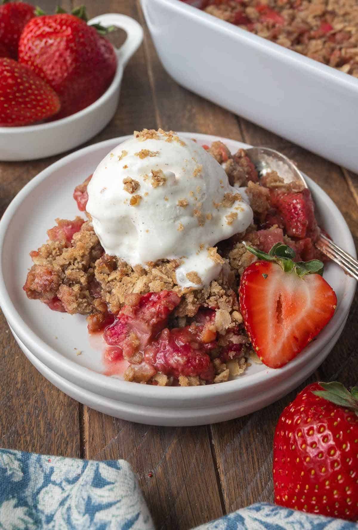 Strawberry rhubarb crisp on a plate with vanilla ice cream.