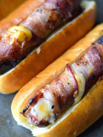 Bacon wrapped hot dogs stuffed with cheese in soft buns