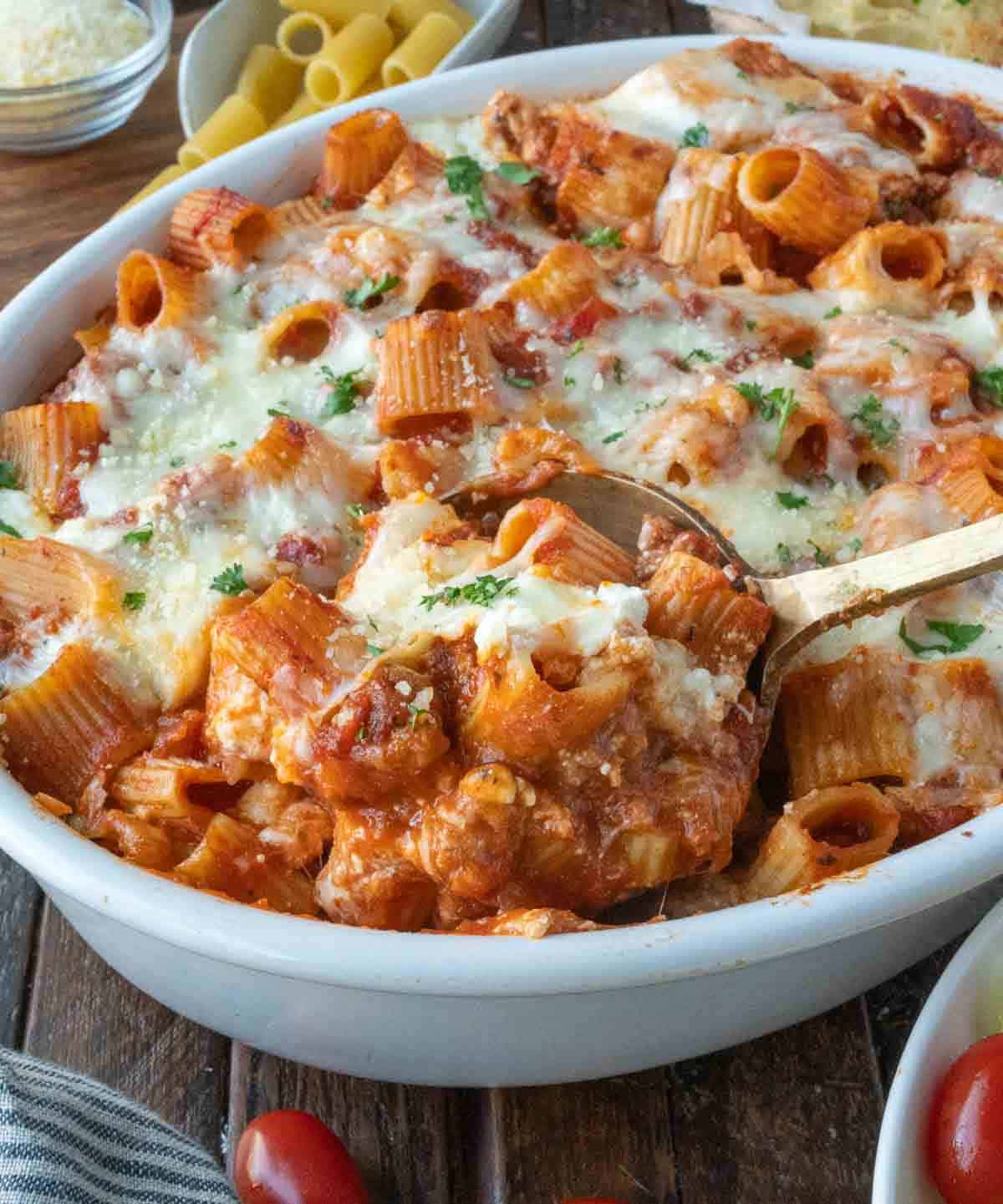 Baked ziti being scooped out of a dish.