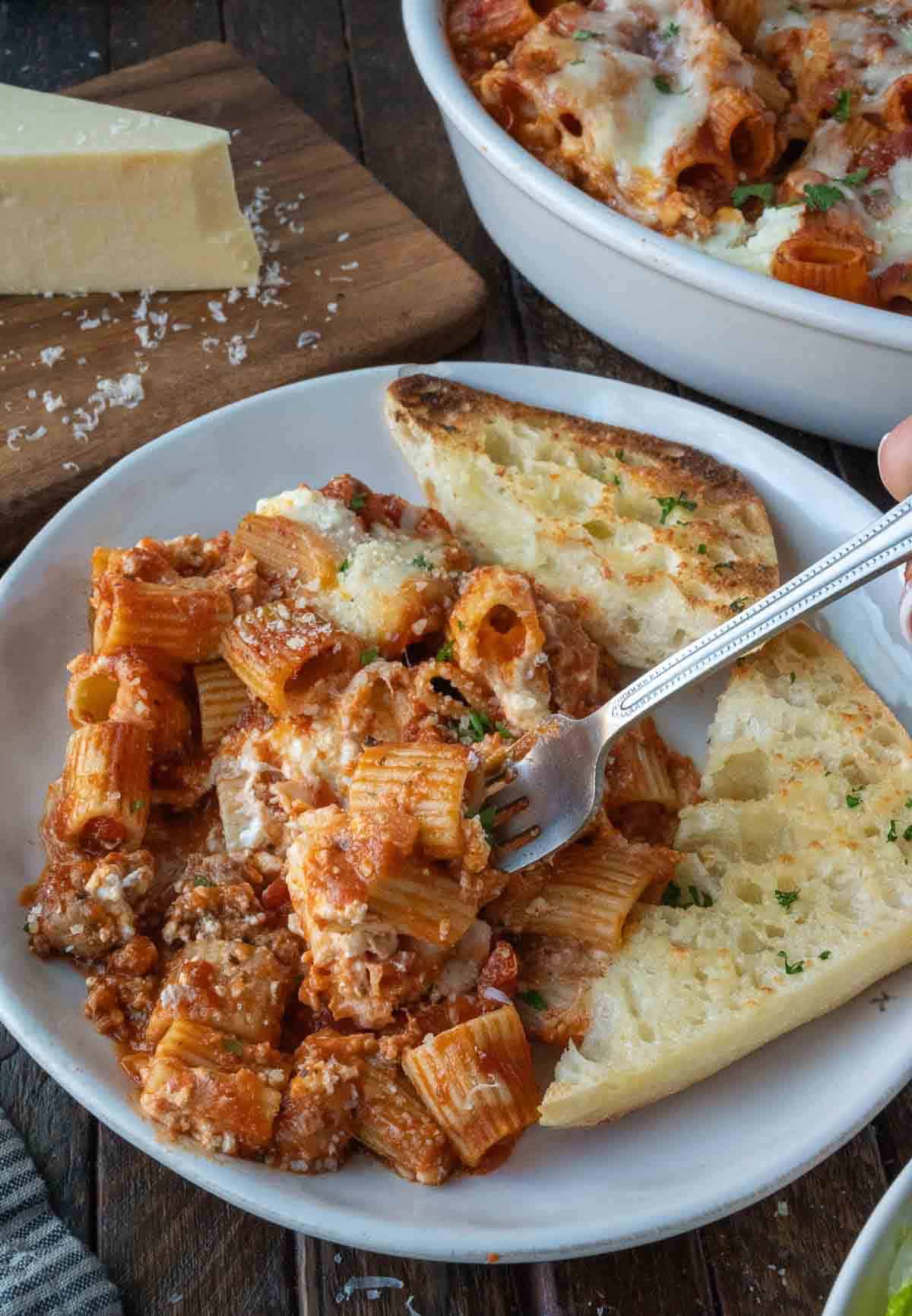 Italian sausage baked ziti on a plate with garlic bread.