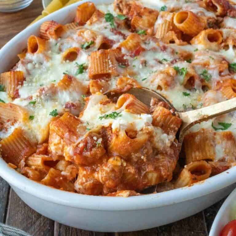 A serving spoon scooping up some baked ziti.