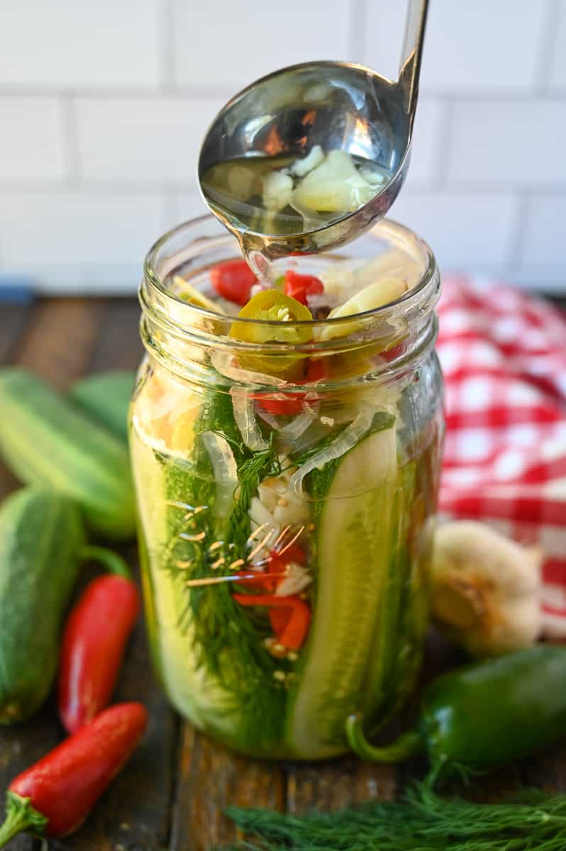 The brine being poured into the mason jar.