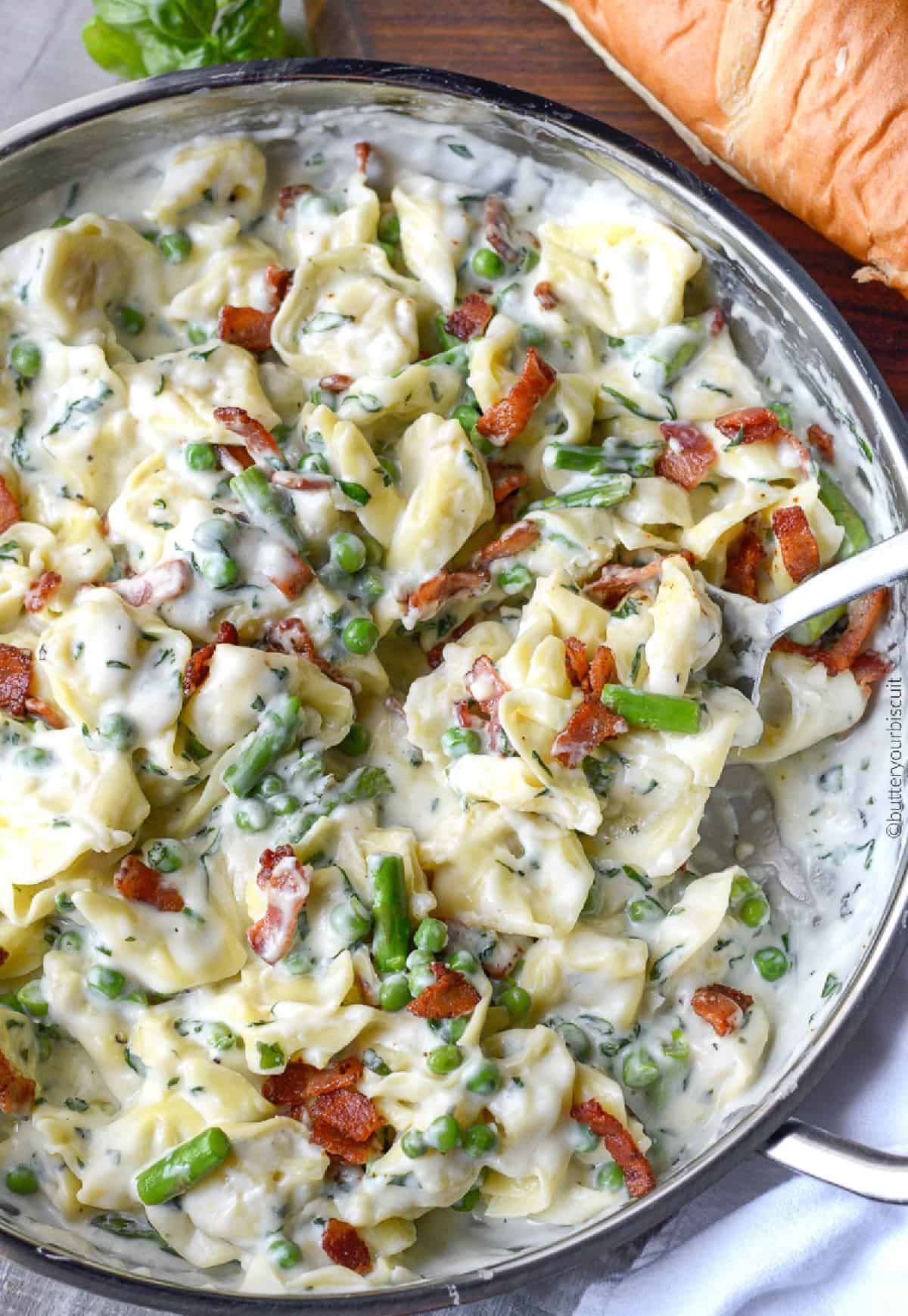 Garlic parmesan cheese tortellini in a skillet with a spoon in it.