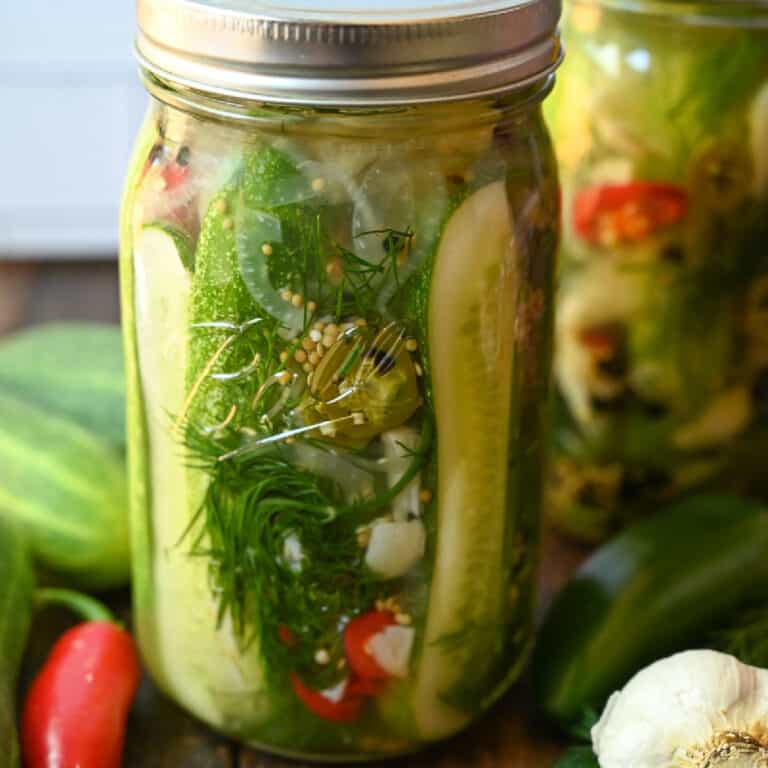 A mason jar filled with sliced cuccumbers, garlic and jalapenos.