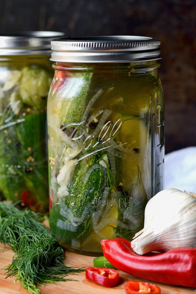 A mason jar filled with sliced cuccumbers, garlic cloves and sliced jalapenos.