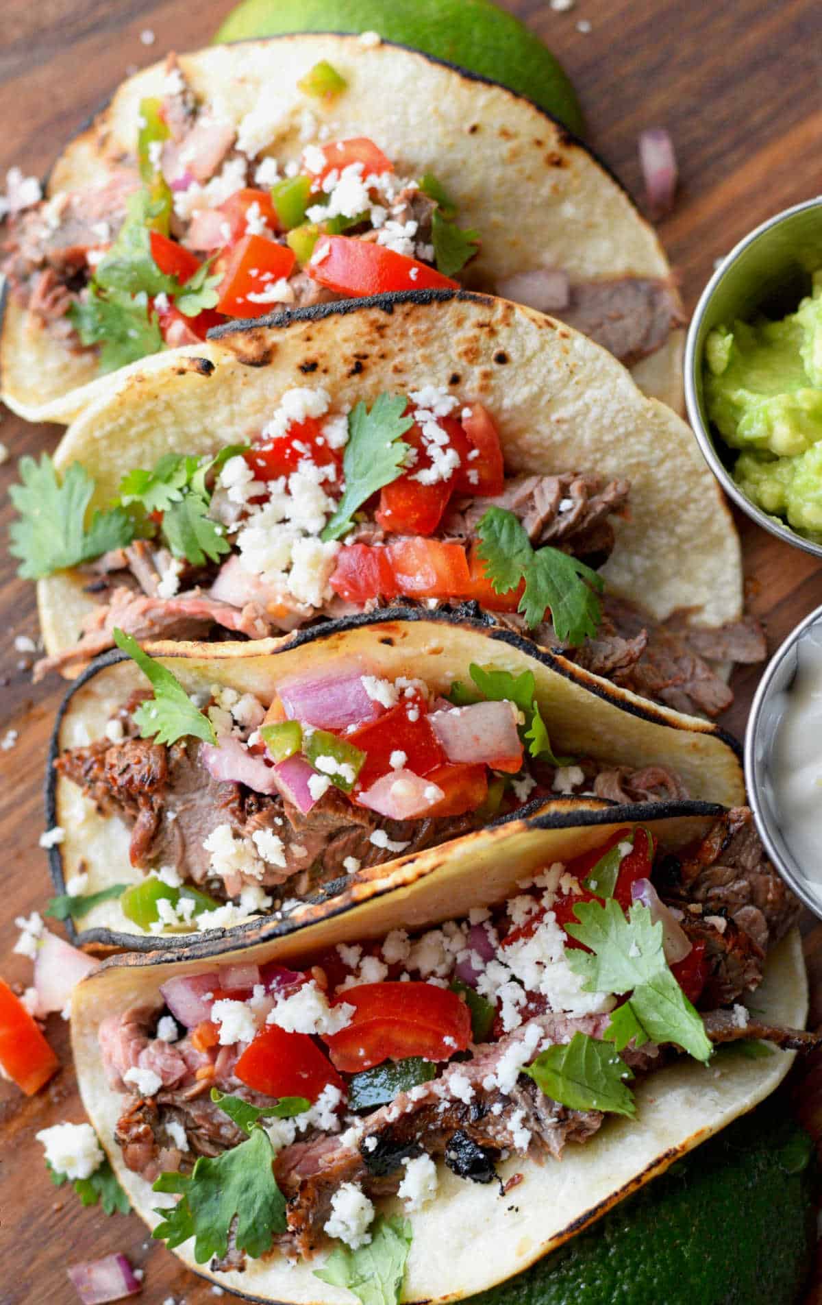Four steak tacos next to each other.