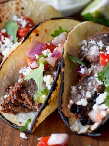 Steak tacos with a side of sour cream.