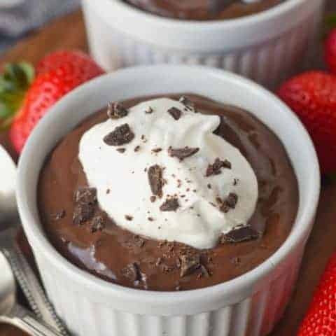 A bowl of chocolate pudding with strawberries on the side.