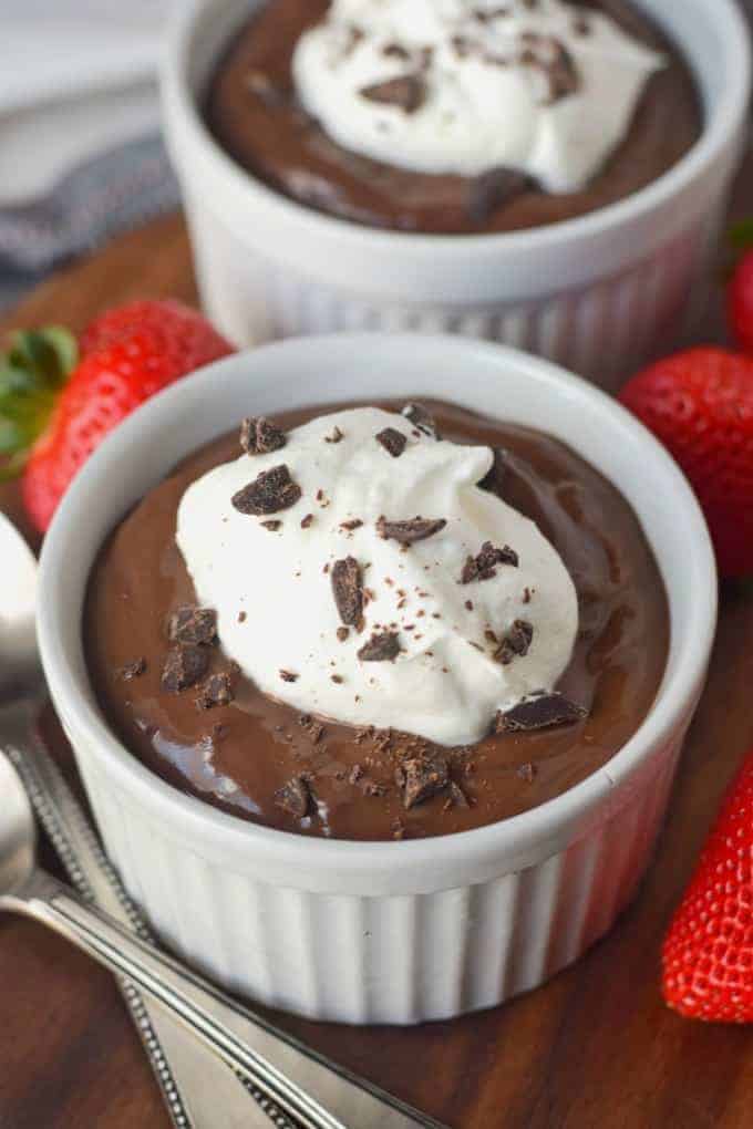 A bowl of chocolate pudding with strawberries on the side.