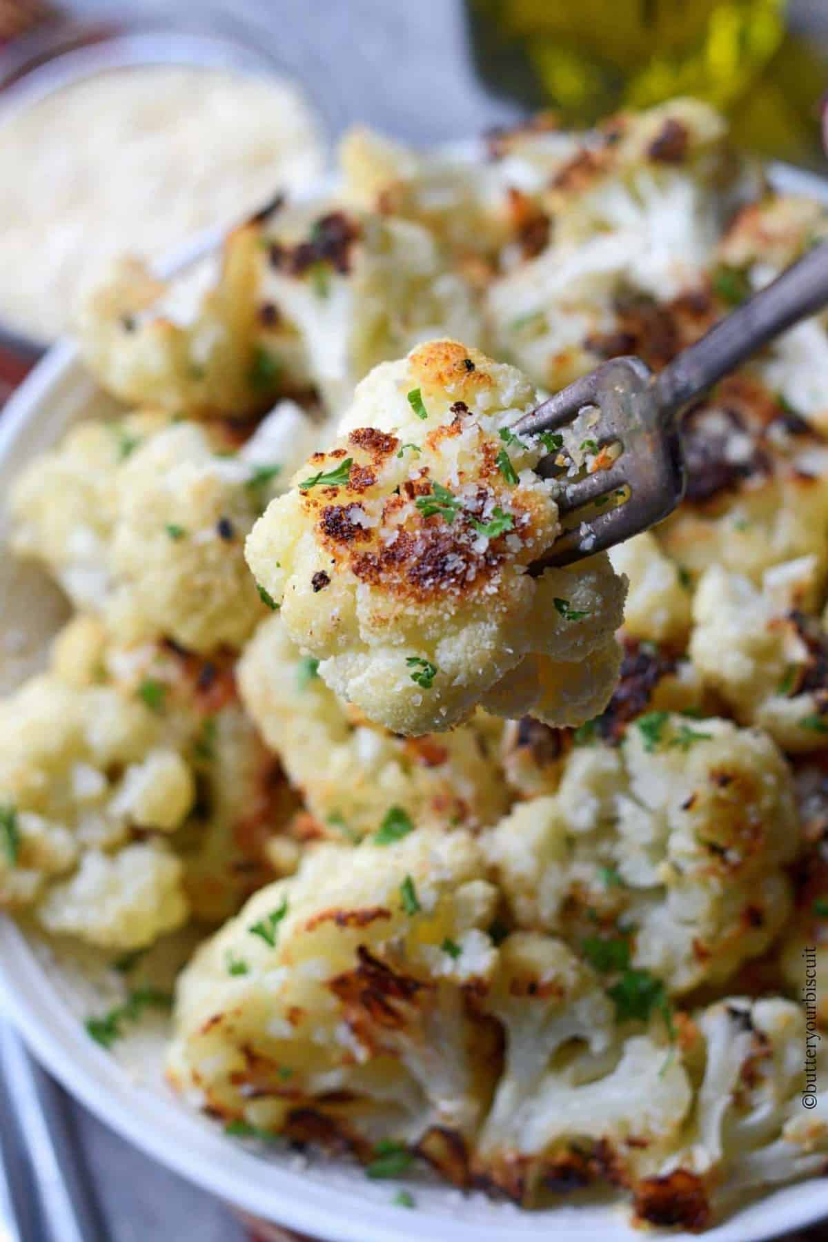 A fork picking up a piece of roasted cauliflower.