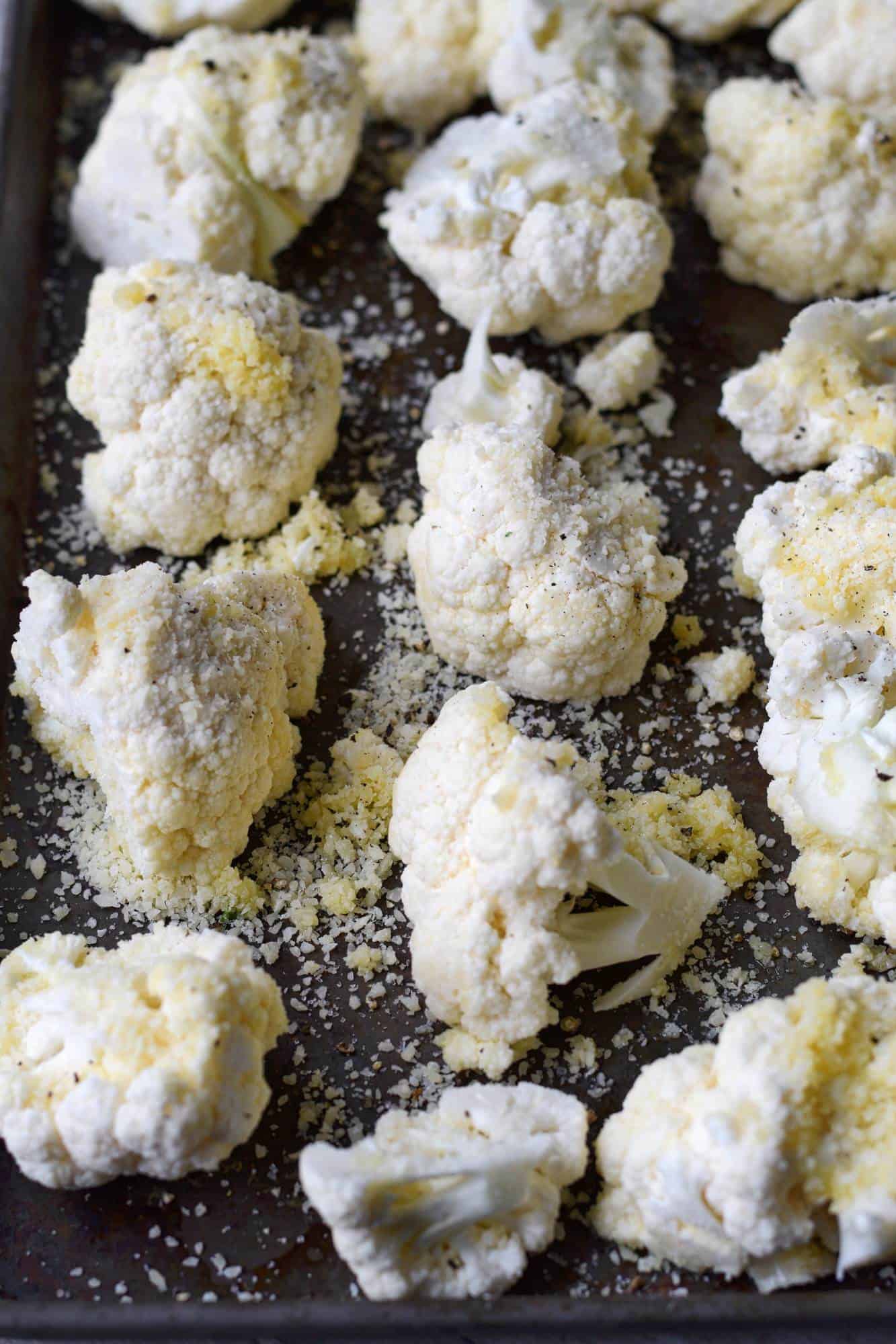 A baking sheet with raw cauliflower tossed in parmesan cheese.