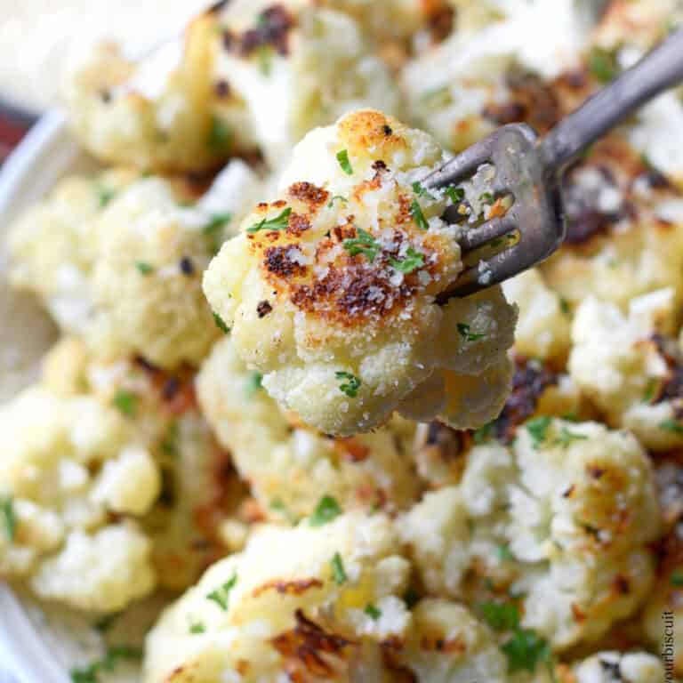 Parmesan roasted cauliflower in a white bowl with a fork grabbing one.