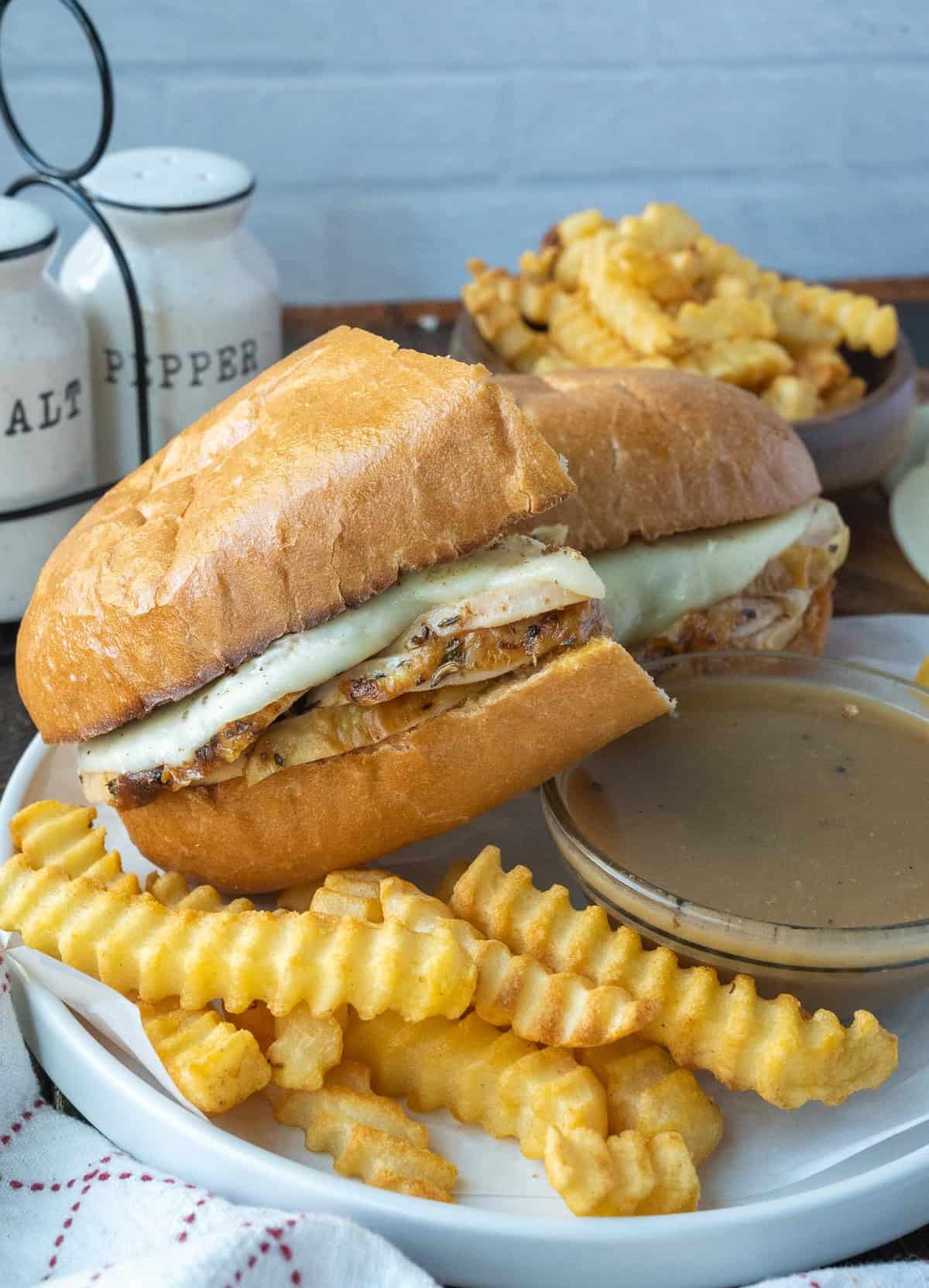 Turkey sandwich on a plate with fries and gravy.