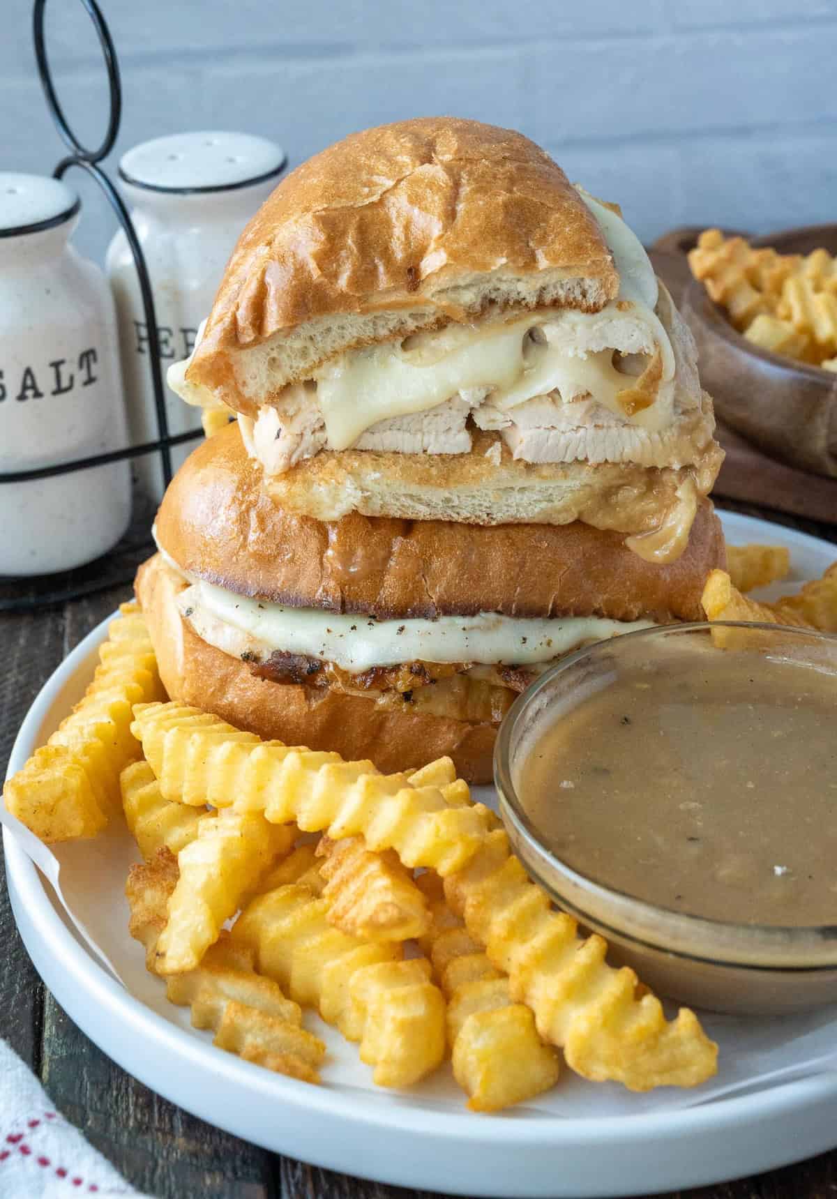 Turkey sandwich stacked on a plate with a side of gravy.