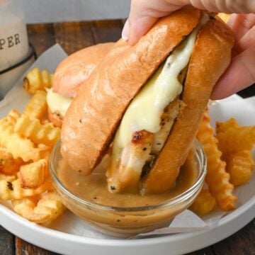 Hot turkey sandwich being dipped into gravy.