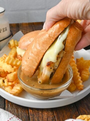 Hot turkey sandwich being dipped into gravy.