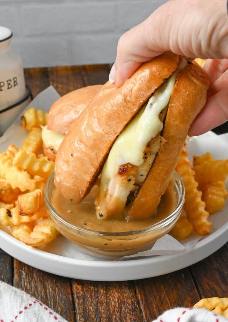 Hot turkey sandwich being dipped into gravy.