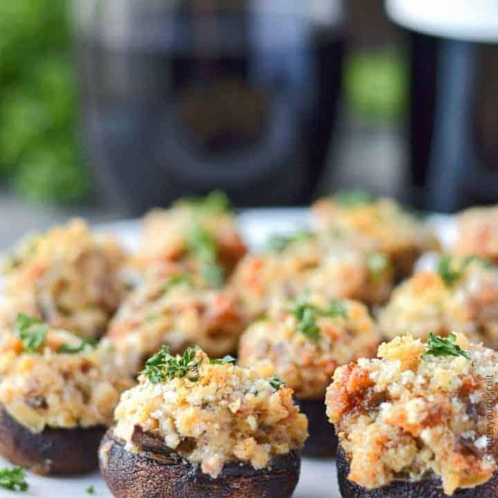 italian sausage stuffed mushrooms on a serving plate with wine